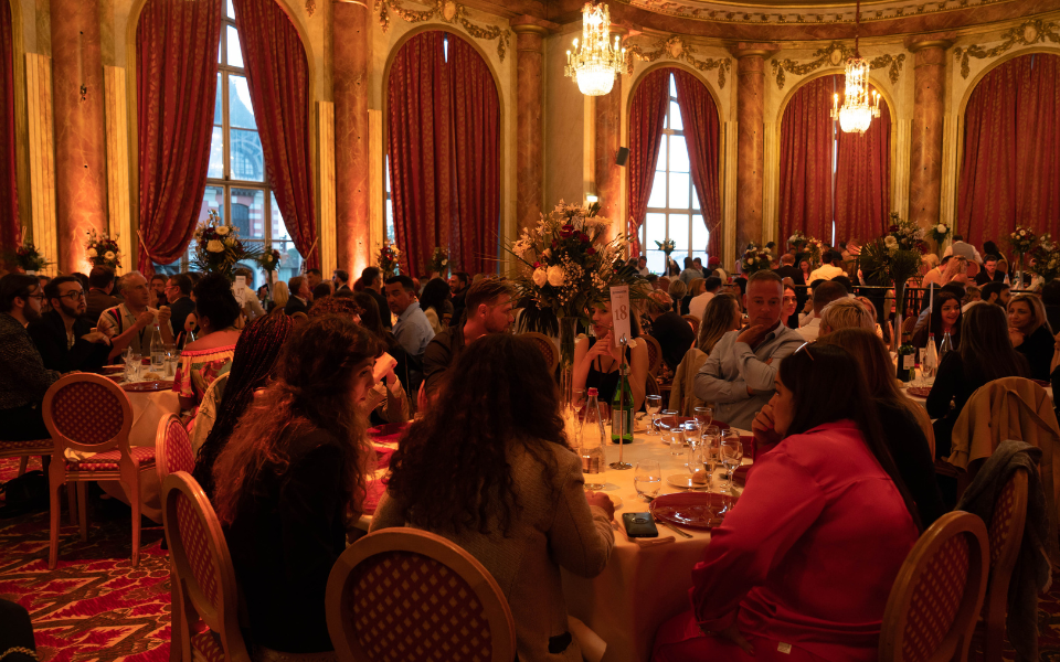 Repas gala au BS Congress, dans une salle somptueuse avec une grande hauteur sous plafond. La salle rappelle les salon chaleureux des grandes demeures : lustre et grandes fenêtres drapées de rideaux rouges bordeaux